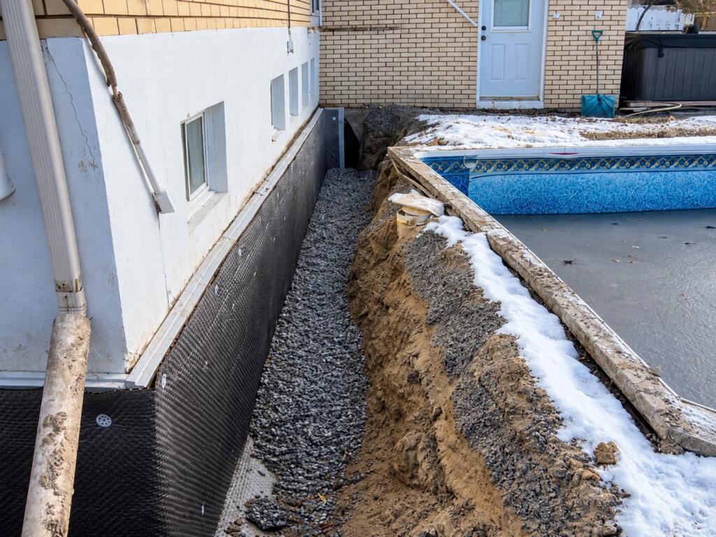 Tranchée de drain français avec pierre concassée et membrane de fondation